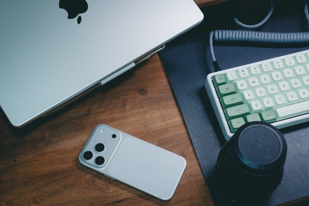 Silver smartphone and laptop on wooden desk.