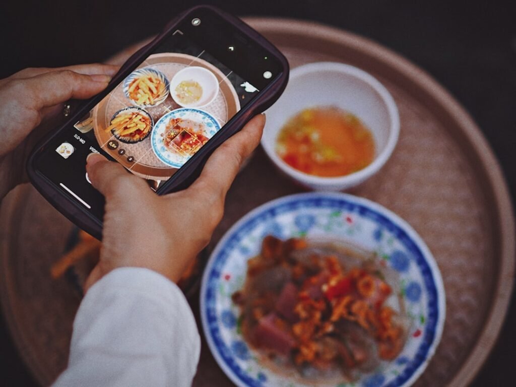 Hands holding a phone taking a picture of food