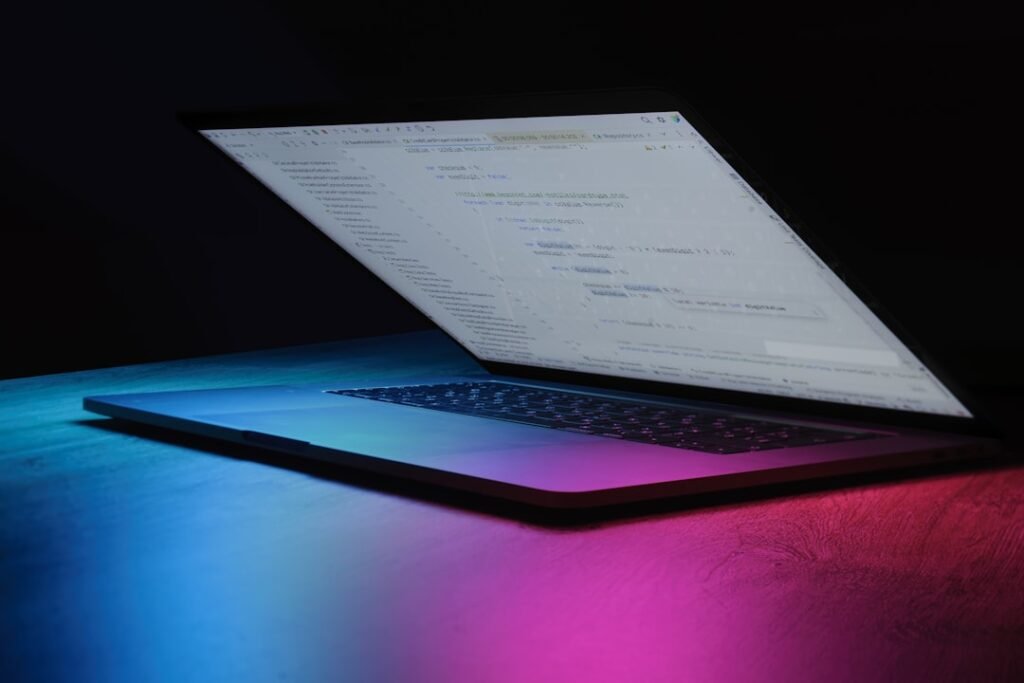 Open laptop with code on screen, neon lighting
