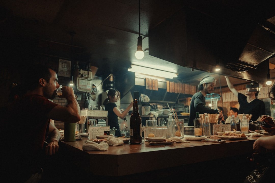 People enjoying drinks and food at a dimly lit bar.