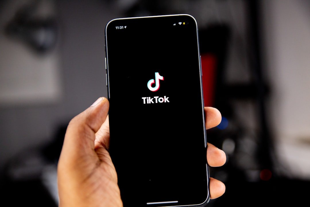 A hand holding a smartphone displaying the TikTok logo on a black screen