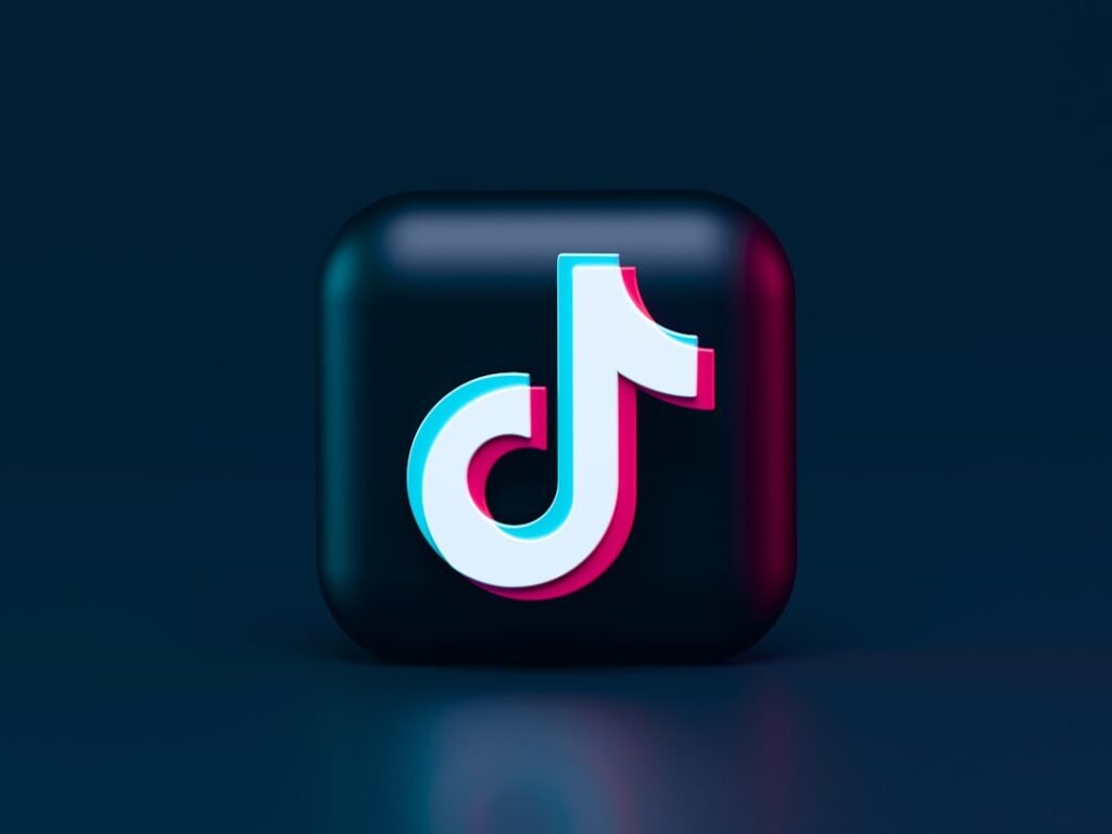 A three-dimensional TikTok logo with cyan and magenta chromatic aberration on a dark background